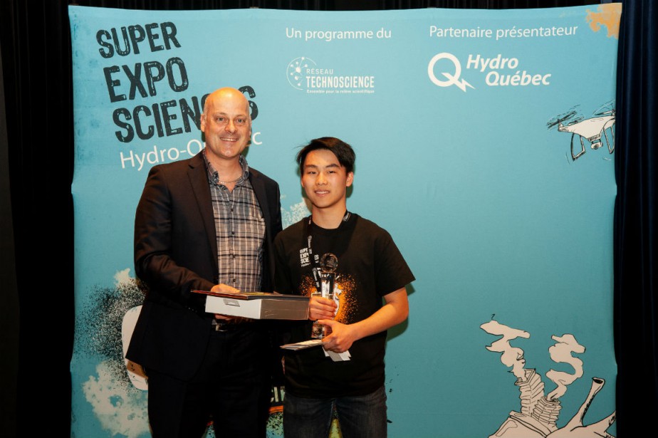 Stephen Lu tient son trophée dans la main droite. À côté de lui, Alain Croteau.